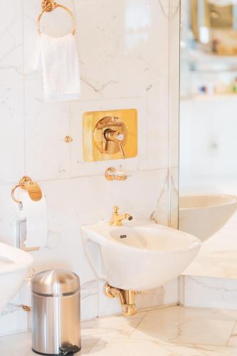 a white bathroom with a sink and a mirror at Grand Hotel National Luzern in Luzern