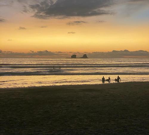 a group of people walking on the beach at sunset at Las Golondrinas Ayampe in Ayampe