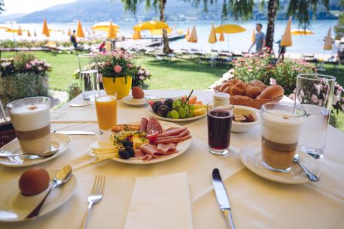 a table topped with plates of food and drinks at Werzers Seehotel Wallerwirt in Techelsberg am Worthersee