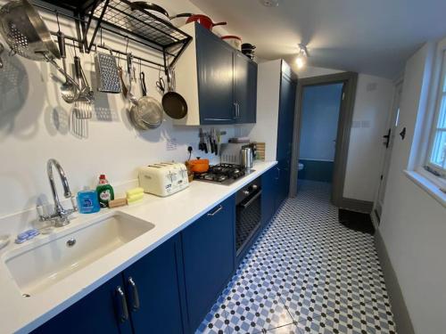 a small kitchen with blue cabinets and a sink at Mary's Cottage in Kingsdown