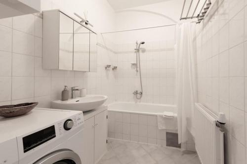 uma casa de banho branca com um lavatório e uma máquina de lavar roupa em Cozy Home Vienna em Viena