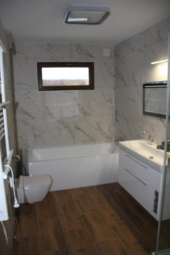 a bathroom with a tub and a toilet and a sink at Apartamenty Twoje Mikołajki in Mikołajki