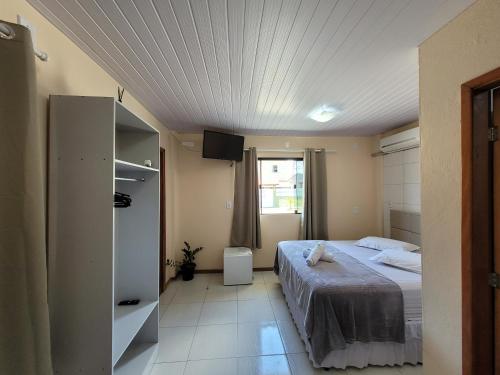 a bedroom with a bed and a tv on the ceiling at Pousada Pontal da Armação in Penha