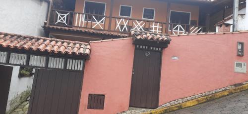 un edificio con una puerta negra y una pared rosa en chalé do Radiola en Ilhabela