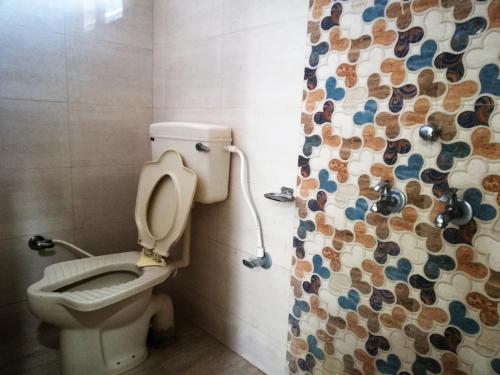 a bathroom with a toilet and a shower curtain at Hotel Shiv Regency in Kukma