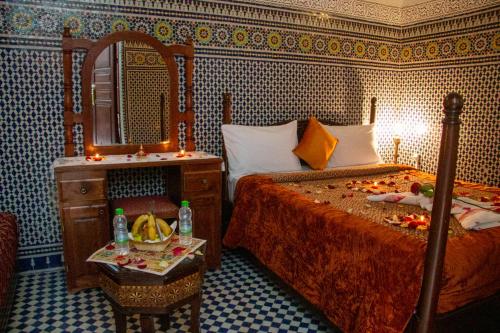 a bedroom with two beds and a mirror and a table at Riad Baba in Fès
