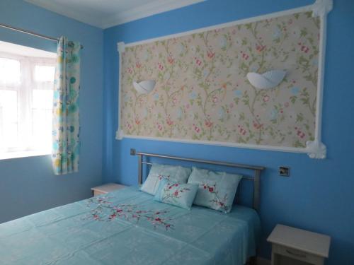 een blauwe slaapkamer met een bed met bloemen aan de muur bij Apsara Villas in Flic-en-Flac
