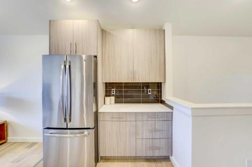 a kitchen with a stainless steel refrigerator and wooden cabinets at Beautiful Townhome - Steps to Downtown Boise! in Boise