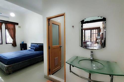 a bedroom with a glass table and a bed and a mirror at Villa 5 BR utk Family/Grup di Villa Citra, Lampung in Tanjungkarang