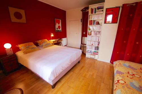 1 dormitorio con cama blanca y pared roja en L ESCALE EN BEAUCE, en Maisons