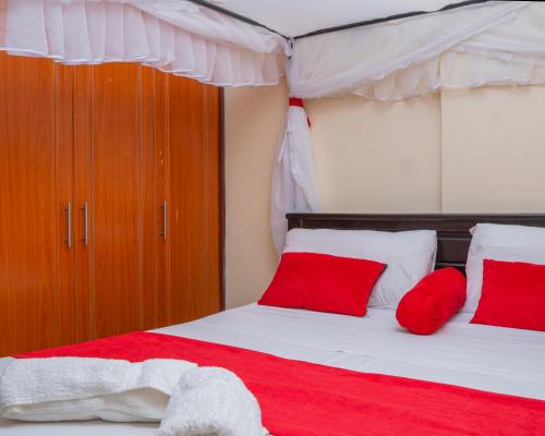 a bedroom with red and white pillows on a bed at Cassabella Apartment, Opposite Metropark Hotel in Kisumu