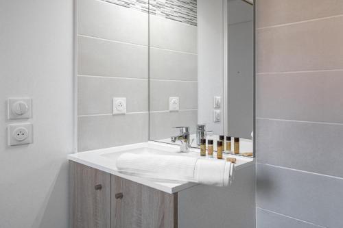 Baño blanco con lavabo y espejo en La Maison Des Lys YourHostHelper en Gujan-Mestras