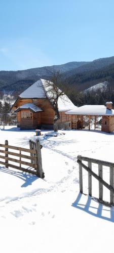 ein Holzgebäude mit einem Zaun im Schnee in der Unterkunft Kuca Karajic in Užice