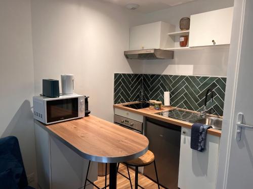 a small kitchen with a wooden table with a microwave at • CosyHouse By Janna • Terrasse - Wifi in Châtellerault