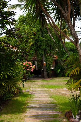 a garden path with palm trees and a building at Pousada Estalagem Vila Tania in Itaúnas
