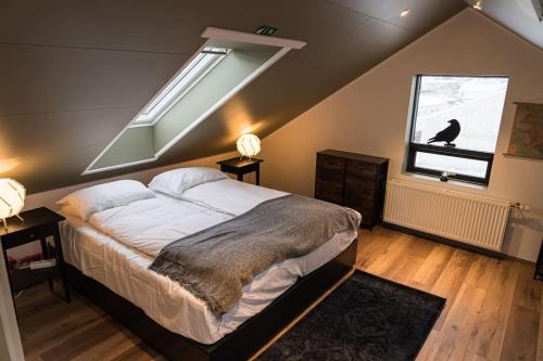 a bedroom with a large bed and a window at Scenic Penthouse - Ocean view & skylight windows in Siglufjörður