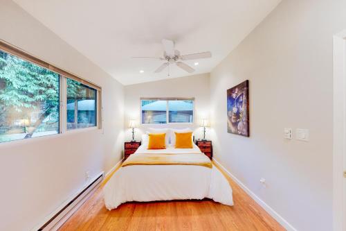 a white bedroom with a bed and two windows at River Paradise in Guerneville