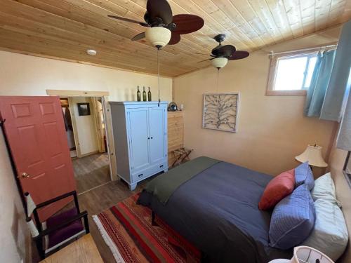 Lava Hideout Cabins في لافا هوت سبرينغس: غرفة نوم بسرير ومروحة سقف