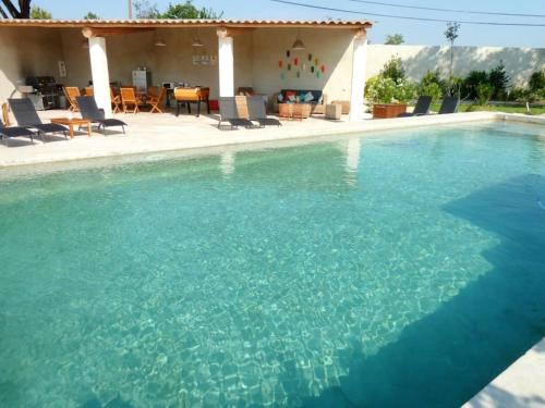 une grande piscine d'eau bleue en face d'une maison dans l'établissement Maison de 6 chambres avec piscine privée, jardin aménagé et wifi à Pernes-les-Fontaines, à Pernes-les-Fontaines