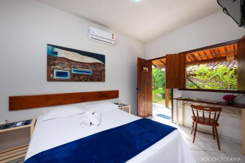 a bedroom with a bed and a desk and a window at Pousada Estalagem Vila Tania in Itaúnas