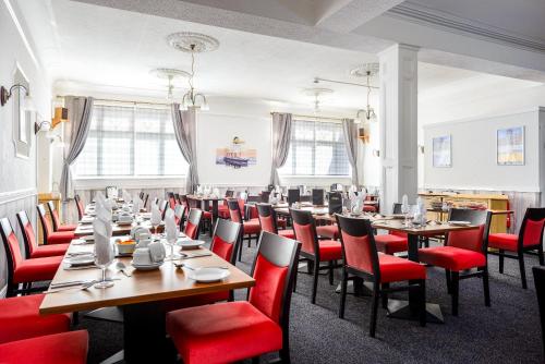 a restaurant with wooden tables and red chairs at Somerset Hotel in Llandudno
