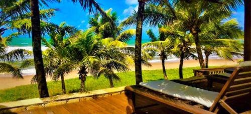 a balcony with a bench and palm trees and a beach at Pousada Luar da Praia in Imbassai