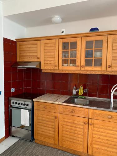 a kitchen with wooden cabinets and a sink at Lovely and Cozy Quiaios 1 Bed Apartment in Palheiros de Quiaios
