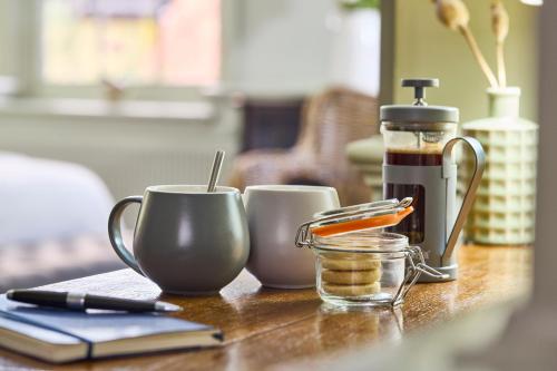 uma mesa de madeira com 2 chávenas e comodidades para preparar café em The Mistley Thorn em Mistley