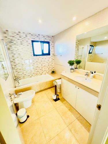 a bathroom with a toilet and a sink and a tub at Sunny Castillo Apartment in Costa de Antigua