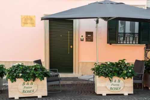 a table with an umbrella and two plants in boxes at B&B Piazza Roma in Norma
