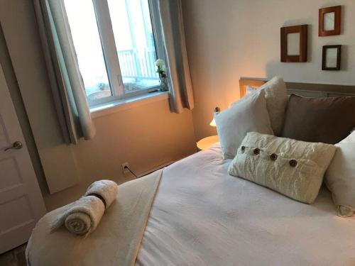 un letto bianco con un asciugamano arrotolato sopra di Condo entier, fully equiped pool and Spa only in summer a Mont-Tremblant