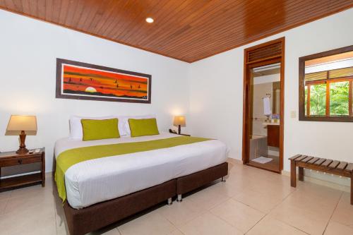 a bedroom with a large bed and a bathroom at Hotel Campestre La Potra in Villavicencio