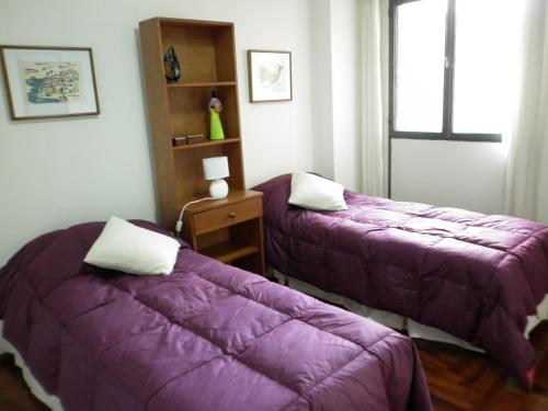 two beds in a room with purple blankets at DEPARTAMENTO EN NUEVA CORDOBA - Bvd Chacabuco in Cordoba