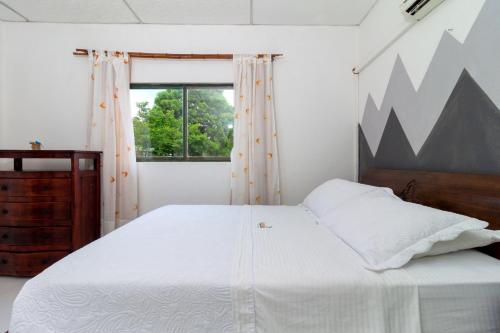 a bedroom with a large white bed and a window at EcoHotel La Fortuna 