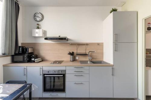a kitchen with white cabinets and a sink at La Maisonnette Du Parc in Le Creusot