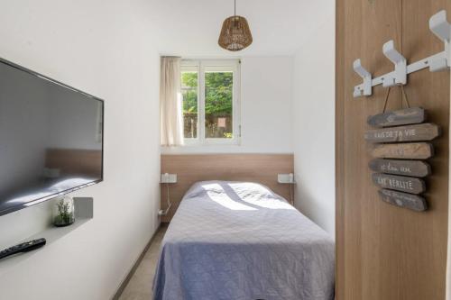 a bedroom with a bed and a tv and a window at La Maisonnette Du Parc in Le Creusot