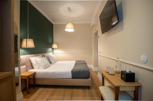 1 dormitorio con 1 cama, TV y mesa en Rossio FLH Suites en Lisboa