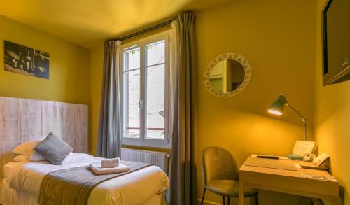 a bedroom with a bed and a desk and a window at Le Central Boutique Hôtel in Beaune