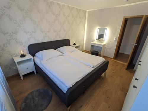 Schlafzimmer mit einem Bett mit weißer Bettwäsche und einem Spiegel in der Unterkunft Bis zu 6 Personen, Bahnhofs- & Zentrumsnah, Südheide, Netflix und PS4 in Celle