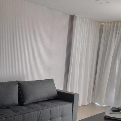 a living room with a couch and white curtains at Apartamento Central em Canela in Canela