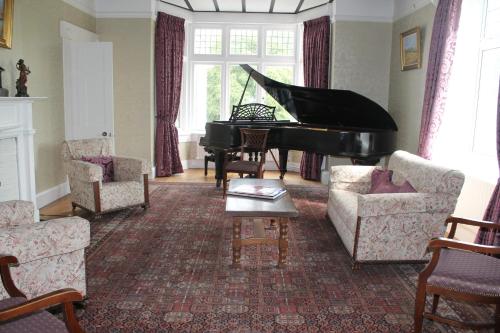 a living room with a piano and chairs at Riversdale Farm B&B in Ballinamore