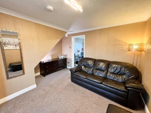 a living room with a leather couch and a mirror at Taylor Close in Fishtoft