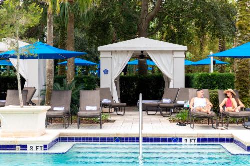twee personen in stoelen naast een zwembad bij Omni Orlando Resort at Championsgate in Kissimmee