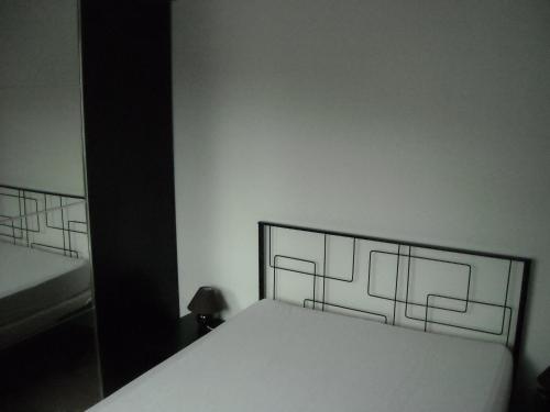 a bedroom with a white bed with a black headboard at Les granvillaises in Granville
