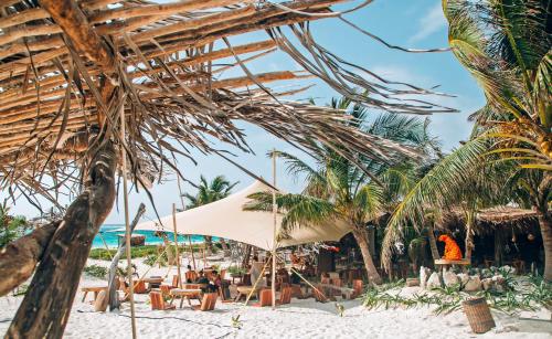 una playa con sillas, sombrillas y palmeras en Ikal Tulum Hotel en Tulum