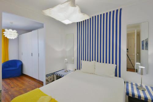 a bedroom with a white bed and a blue and white striped wall at FLH Norte Place in Lisbon