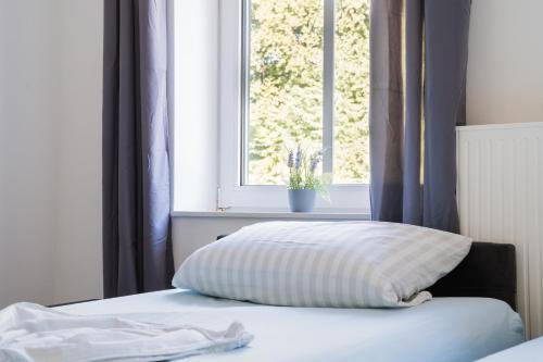 a bed with a pillow in front of a window at Buer Appartment in Gelsenkirchen