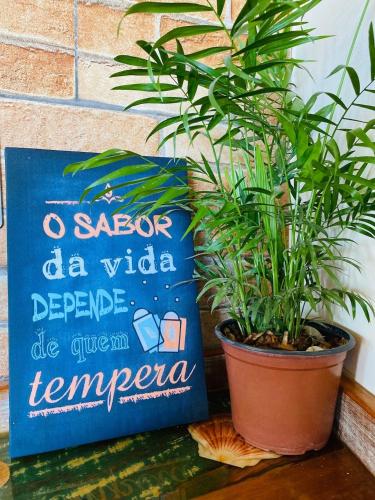a sign next to a potted plant next to a plant at Apartamentos exclusivos e equipado com varanda ou terraço com Pôr do sol, cozinha privativa, Wi-Fi 600MBs, a 700m da praia de Itapirubá e 1km da BR-101 in Imbituba