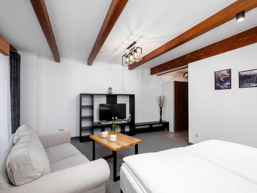a living room with a white couch and a tv at Villa Taternik by Golden Apartments in Zakopane
