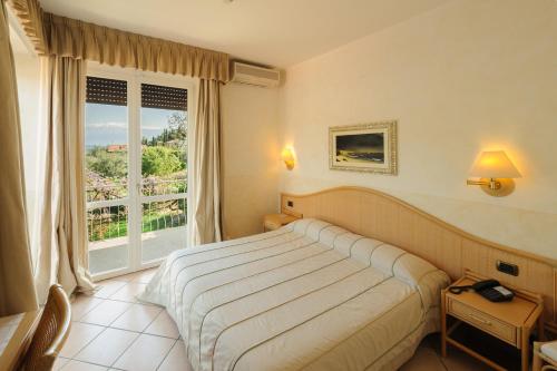 - une chambre avec un lit et une grande fenêtre dans l'établissement Hotel Garden Zorzi, à San Felice del Benaco